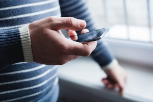 The man is using a smartphone. Modern mobile phone in hand.